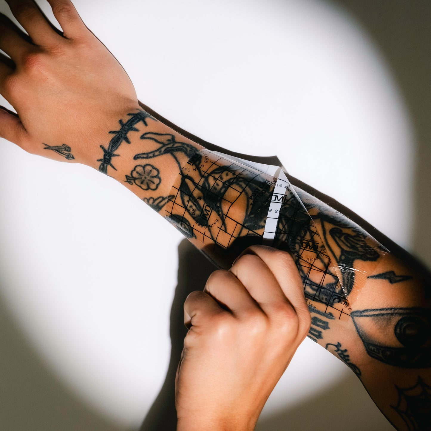 Applying IMD Post Care Tattoo Patch over a fresh sleeve tattoo — ultra-thin, breathable wrap for new ink aftercare