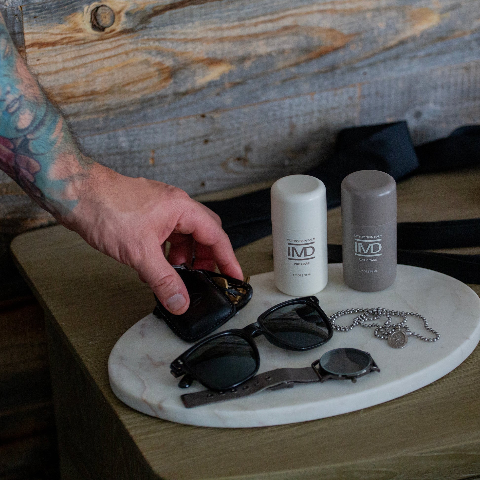IMD Pre Care and Daily Care Tattoo Balms on a marble tray — part of a daily skincare routine for tattooed individuals